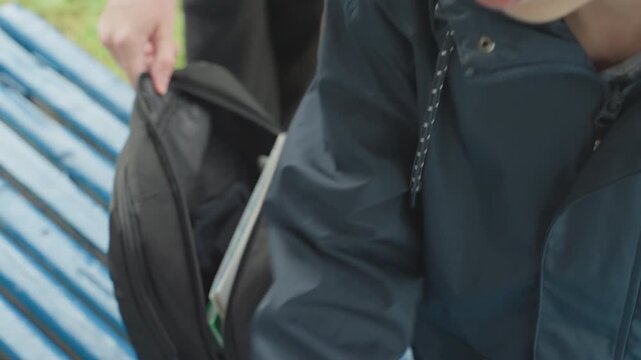 Young learner packs belongings efficiently. Pupil arranges school supplies carefully before departure. Child meticulously organizes notebooks and supplies in backpack before leaving for school