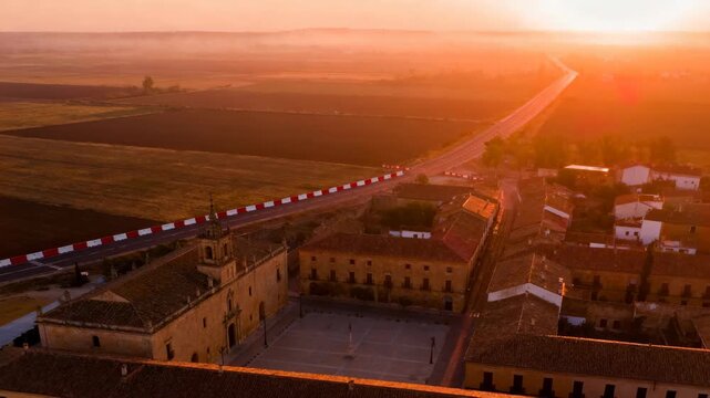 aerial view of zamora at sunset, warm golden light over colonial rooftops and surrounding farmland, mexico