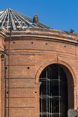 Naklejka premium Roofer Working on Steel Frame of Dome Building Under Blue Sky