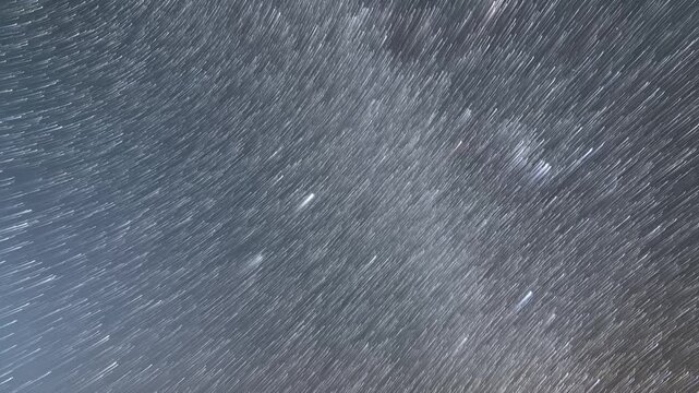 Time-lapse of rotating starry sky with star trails, dreamy cosmic night sky and long exposure light trails