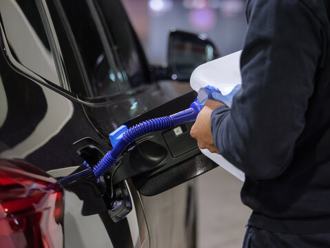 Filling diesel exhaust fluid in a car close-up. Refilling the AdBlue tank manually at a gas station in Germany. Chemicals based on an urea solution to reduce the exhaust emissions (nitrogen oxides).