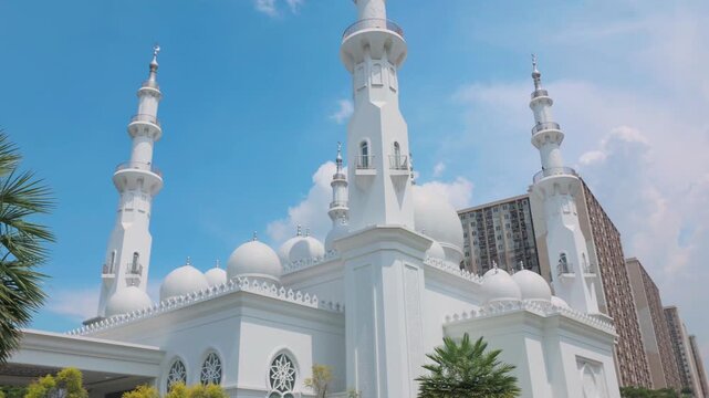 Depok, Indonesia (April 6, 2026): At-Thohir Mosque, A stunning white mosque featuring elegant domes and towering minarets set against a bright blue sky, showcasing Islamic architectural beauty