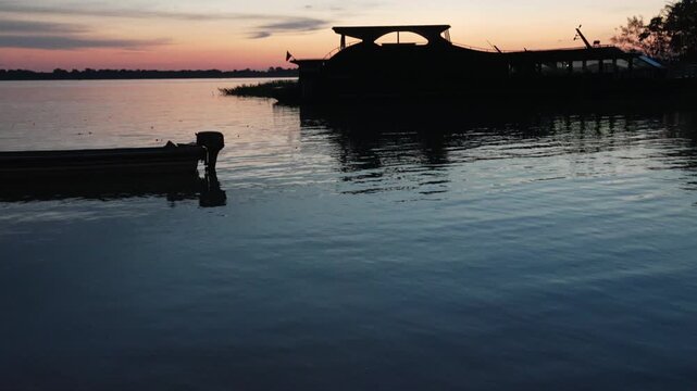 Tilt-up shot of the Amazon River during sunset with small boats