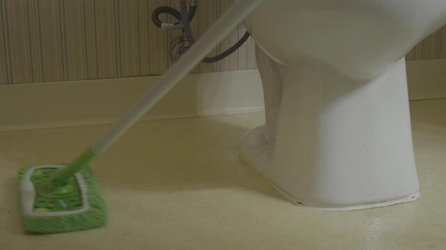 Slow movement of mopping a dirty bathroom floor.