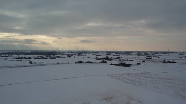 Wide drone shot of wind turbines and sun rays in winter.