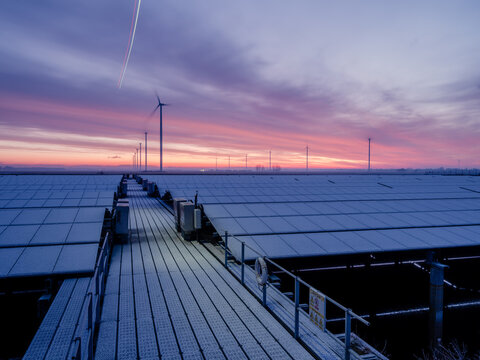 Solar Panels in Winter Frost at Sunrise with Colorful Sky &ndash; Renewable Energy Concept. Solar panels covered with frost in a winter landscape during sunrise, illuminated by a colorful dramatic sky. 
