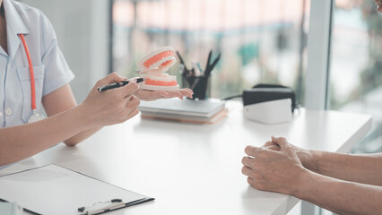 The patient is discussing their dental treatment plan at the dental clinic. During the discussion about dental treatment, the dentist and patient are conversing with a model on the table.