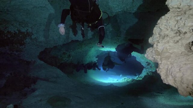 Diver lights cave walls and floor while moving through submerged cavern in Cenote Dos Ojos, Quintana Roo, Mexico