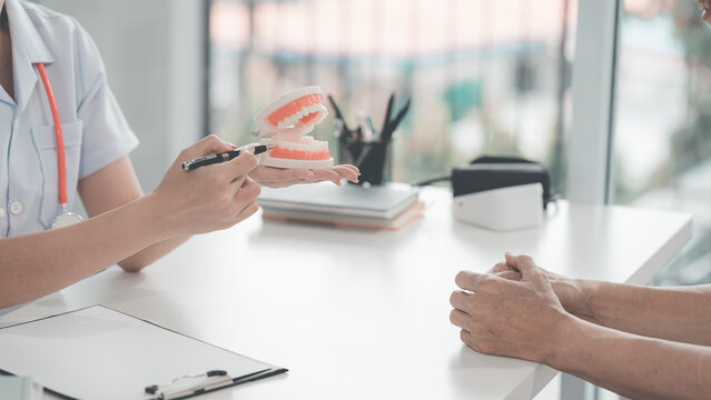 The patient is discussing their dental treatment plan at the dental clinic. During the discussion about dental treatment, the dentist and patient are conversing with a model on the table.