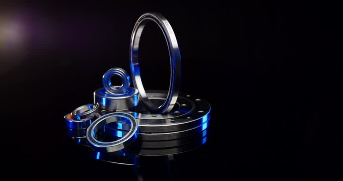 Selection of high-precision industrial ball bearings and metal flanges with blue light accents in a dark studio