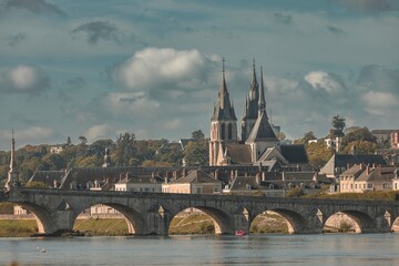 Obraz premium As twilight gently embraces the landscape, the enchanting silhouette of towers rises above charming homes by the river. Soft reflections dance on the water, capturing a moment of tranquility