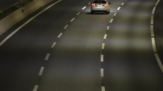 MADRID, SPAIN - JANUARY 13, 2026: Car driving on a multilane urban highway at night, red tail light visible on dark asphalt with white dashed lane marking, light traffic conditions