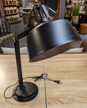 L&aacute;mpara ajustable de metal negro en mesa de madera en tienda de muebles y decoraci&oacute;n 