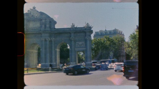 Historic European stone triumphal arch with sculptures and city traffic in the background on analog super 8mm film scan
