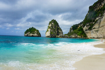 Obraz premium Beautiful tropical shoreline with turquoise waves, white sand, and dramatic limestone rock formations. Perfect for travel, tourism, and relaxation concepts.