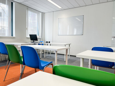 A well-lit contemporary classroom equipped with a large whiteboard for writing, ergonomic student desks and chairs, and flexible space for group activities or presentations. 
