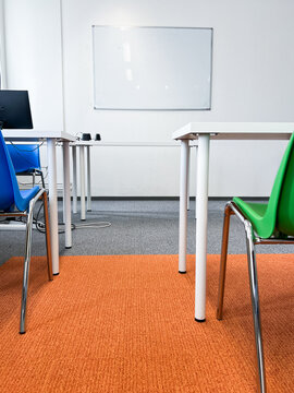 A well-lit contemporary classroom equipped with a large whiteboard for writing, ergonomic student desks and chairs, and flexible space for group activities or presentations. 