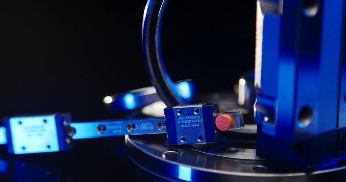 Close-up of a high-precision linear guide rail with two miniature carriages and blue lighting