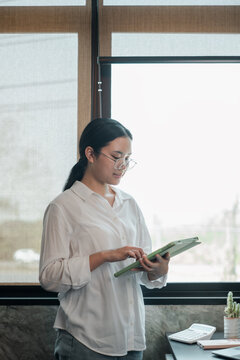 Businesswoman in a bright office using a tablet, showcasing modern work environment and technology.