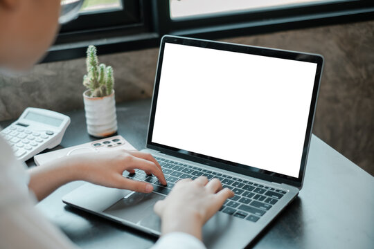 Individual working on a laptop with a blank screen in a bright, modern office setting.