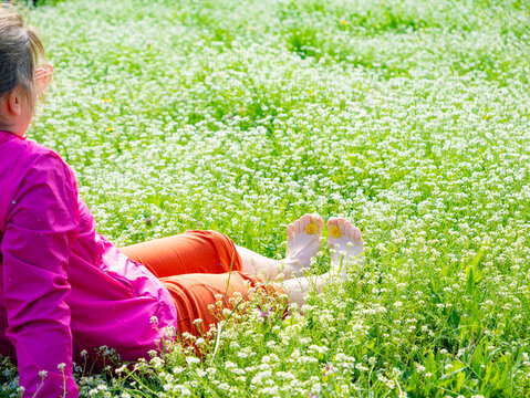 Person relaxing in nature on spring grass with flowers outdoors