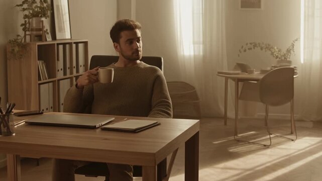 Individual Enjoying Morning In Cozy Office. Person Seated Peacefully At Desk With Sunlight Streaming In