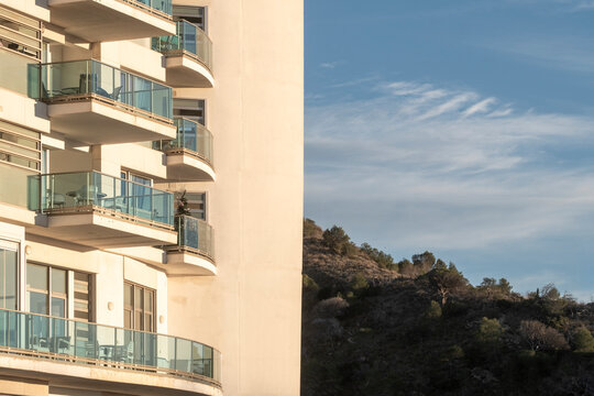 Residential architecture in spain with modern apartment building facade where balconies wrap a corner volume above a quiet hillside setting