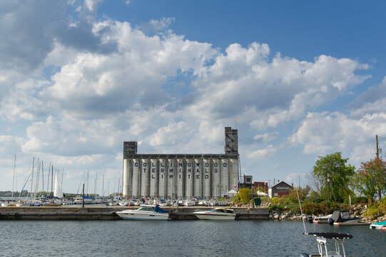 Historic grain elevator at Collingwood Ontario marina with sailboats docked under dramatic blue sky with white clouds on a warm autumn day by the waterfront