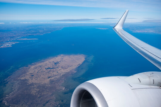 Clean commercial airplane wing flight travel aerial above coastline ocean horizon and sky showing transport in Denmark modern aviation view
