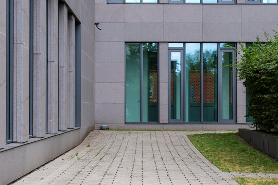 Empty modern urban courtyard with entrance and building over pavement showing minimal architecture space and clear wayfinding for city access route