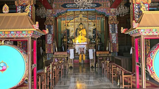 Interior of a Buddhist temple featuring a golden Buddha statue, colorful decorations, and prayer seating. Spiritual and peaceful ambiance ideal for religion, meditation, Bodh Gaya , Bihar, India