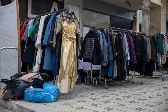 Outdoor clothing rack with various second hand clothes on a city street