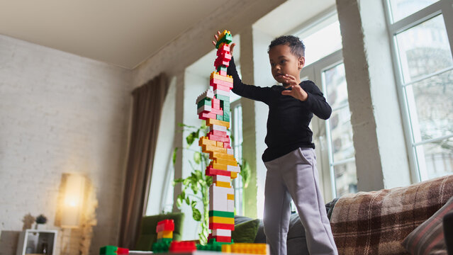 Child stacking very tall tower of colorful blocks at home. Concept of goal achievement, persistence training, focus improvement and educational play for child development.