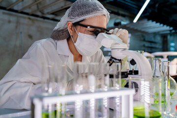 A researcher in a sterile lab conducts a scientific experiment using a microscope and test tubes. Cutting edge biotechnology and chemistry help develop breakthroughs in medicine and healthcare. © ultramansk