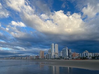 Obraz premium nuvens e ceu azul em um amanhecer na praia com alguns prédios na orla na cidade de Praia Grande