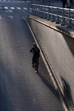 Cyclist in motion seen overhead on modern urban road where asphalt and shadows form a minimalist graphic pattern in stockholm sweden