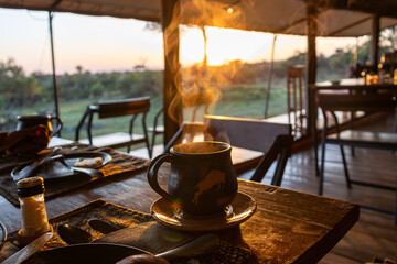 Hot coffee steaming on a dining table at sunrise in a safari tented camp in Serengeti National Park Tanzania © Joao Vieira