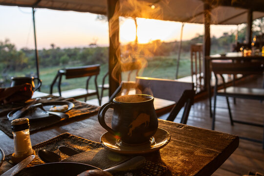 Hot coffee steaming on a dining table at sunrise in a safari tented camp in Serengeti National Park Tanzania