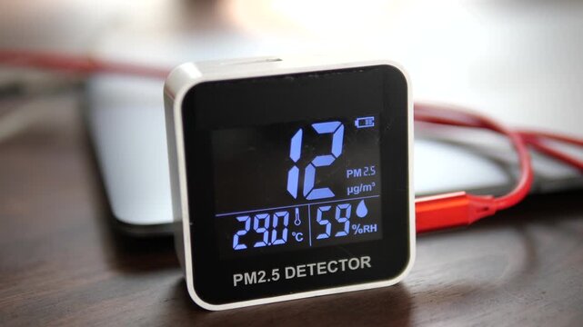 Digital air quality monitor displaying low healthy PM 2.5 levels on wooden surface for clean air and environment concept