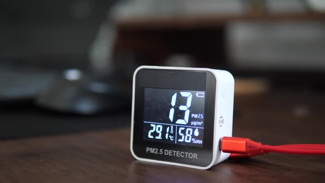 Digital air quality monitor displaying low healthy PM 2.5 levels on wooden surface for clean air and environment concept