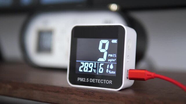 Digital air quality monitor displaying low healthy PM 2.5 levels on wooden surface for clean air and environment concept
