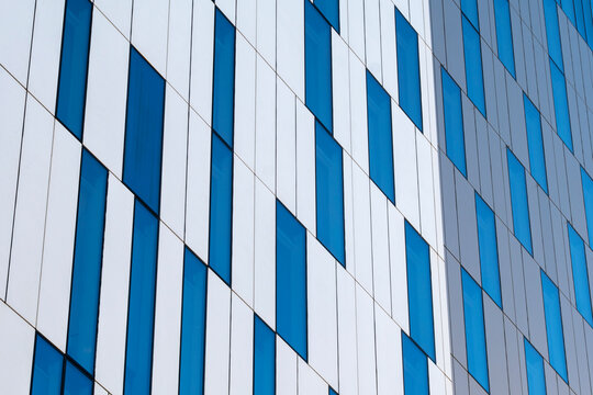 Abstract modern architecture detail in blue stripes on a geometric facade with windows and repeating pattern creating a clean graphic surface