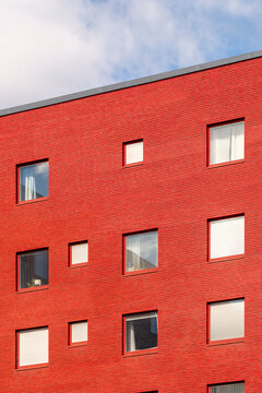 Minimal modern urban architecture with geometric grid windows on red brick facade presenting clean lines texture and simple building exterior detail