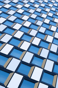 Abstract symmetry in a modern blue architecture facade with geometric grid windows pattern creating a clean urban building surface and design detail