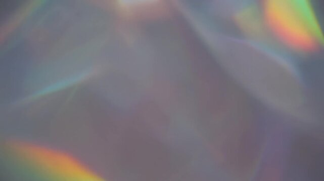 Rainbow light prism refraction patterns dancing gracefully across a smooth neutral wall surface in motion video clip