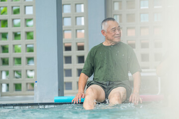 Fototapeta premium Smiling older man enjoying aqua therapy at the pool edge. Active senior in wet clothes kicking water for physical rehabilitation and fitness. Healthy aging and outdoor leisure activity.