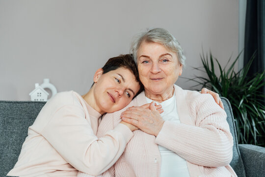 Emotional Adult daughter hugging happy senior 70s mother in cozy interior. Mother day. Happy family enjoying weekend together. Parenting love, care, generations unity. Spending time in retiring house