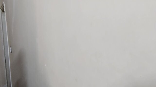 Worker smoothing putty on wall with scraper before paint job
