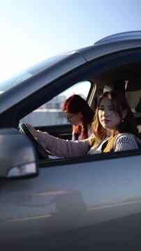 Vertical screen young woman driving car during lesson while instructor sits beside giving directions and observing her actions building confidence and control behind the wheel