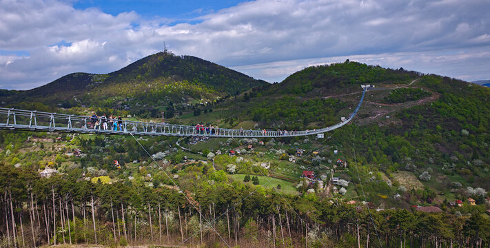 Modern suspension bridge (Hungarian National Unity Bridge)connecting hills above S&aacute;toralja&uacute;jhely, Hungary, with scenic valley, forests and spring landscape under dramatic clouds.